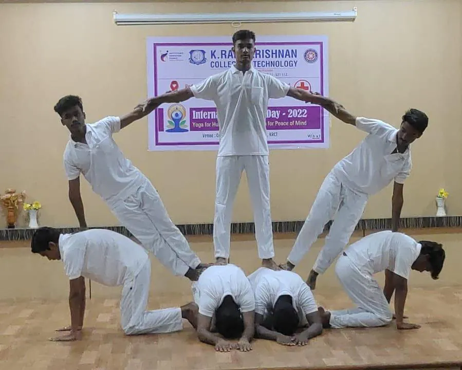 Students in white holding a balanced group formation on stage