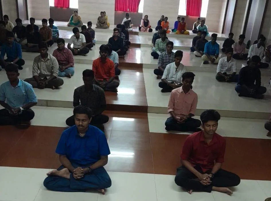 Students seated cross-legged in rows, meditating