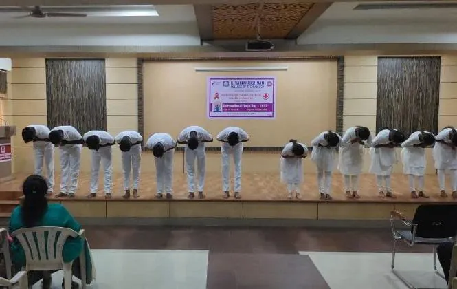 A row of students in white bending forward together