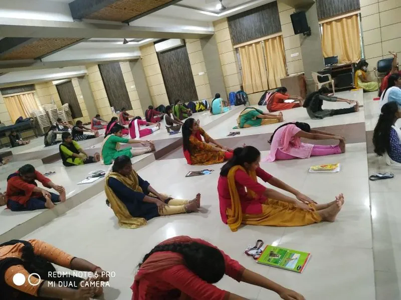 Students practising seated asanas on the floor of the seminar hall