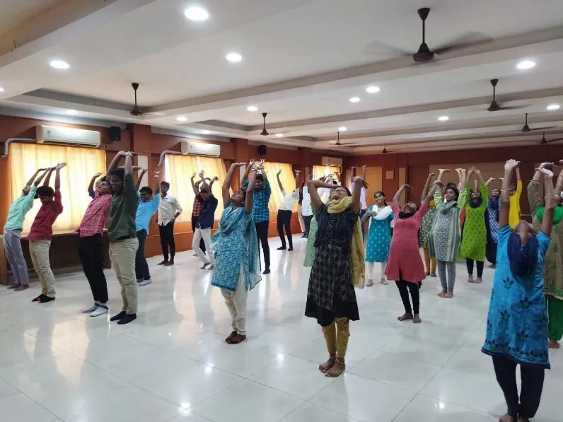 Students standing with arms raised during a yoga session